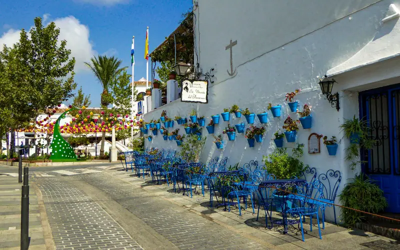 Blue flower pots and café chairs along a white wall in Mijas Pueblo